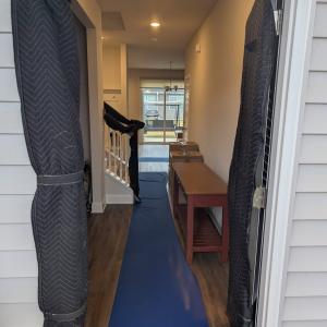 A hallway inside a home is prepped for a move with protective floor runners and door frame padding to prevent damage during the moving process.