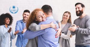 A group therapy session with woman hugging man shows the concept of Icarus Wellness and Recovery offers confidential consultations by phone and accepts many forms of insurance for its programs