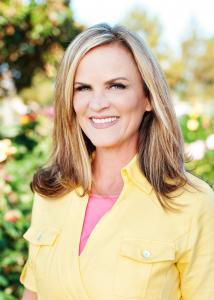 Stephanie Brown, founder and CEO of The Rosie Network, smiling outdoors in a yellow shirt.