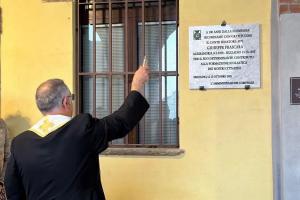 A priest performing a blessing before a marble plaque honoring Count Giuseppe Frascara at the Abbazia di Santa Giustina, Sezzadio.