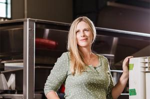 winemaker katy wilson in from of winemaking equipment in winery