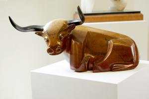 contemporary, stylized, longhorn bull sculpture laying down, in bronze