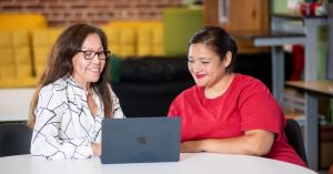 Two people are looking at a laptop. One is a case manager and the other is a client. They are using Benefit Navigator from Amplifi to identify public benefits.