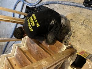 A ServiceMaster Restoration By Simons technician removing wet carpet and debris from a staircase after water damage in Lake Forest, Illinois.