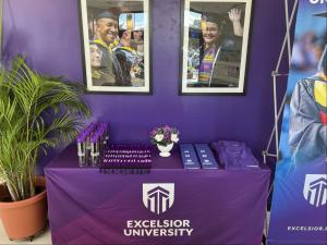 Excelsior University branded table with giveaways and photos of graduates at the Excelsior University St. Petersburg site