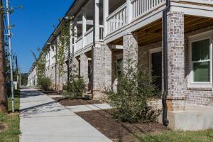 Exterior view of Mitchell Yards student housing in Fayetteville, Arkansas, featuring modern brick townhomes with secure entrances and spacious walkways.