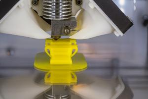 A close-up of a 3D printer creating a bright yellow model, symbolizing innovation and customization in modern marketing and design.