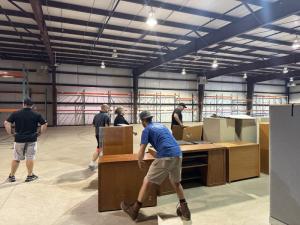 Inside The New Warehouse at Neighborhood Roofing showing men moving office furniture in place
