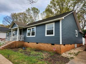 Front and side view of a remodeled Charlotte, North Carolina home with Andersen 100 Series windows, blue James Hardie lap siding, white trim, and a brick foundation installed by Hatch Homes.