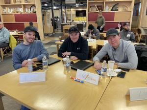 Three Hatch Homes team members seated at a training workshop table with notebooks, drinks, and name tags during an industry education event.