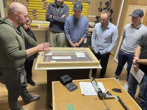 Group of Hatch Homes team members gathered around an Andersen window display during a hands-on installation training session, led by an instructor demonstrating proper techniques.