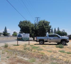 Valley Haul-Off LLC truck parked next to the company sign, representing certified hauling and eco-friendly waste management in the Central Valley.