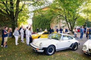 Guests and collectors viewing vintage Porsche and Ferrari in the Villa Badia Sezzadio courtyard during the Wheels Through History event.
