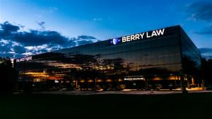 Exterior of Berry Law’s new West Omaha office illuminated at night, featuring modern architecture, large glass windows, and the Berry Law shield logo glowing above the entrance.