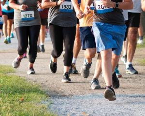 Runners of all ages and abilities participate in an inclusive 5K run and walk event, moving together along a scenic park trail in support of the blind and visually impaired community.