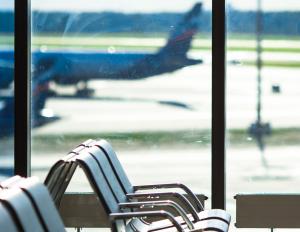 Chair in an airport next to a window with an airplane.