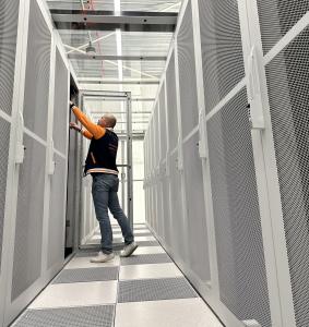 Technical engineer from MIRhosting servicing equipment in a high-density server environment.