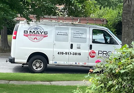 White service van for B. Mays Heating and Air Conditioning parked on a residential street, featuring company logo, contact number, and Rheem Pro Partner branding