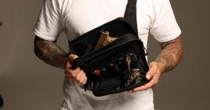 Man holding the SLNT® Concealed Carry Faraday Sling open kitted out with supplies.