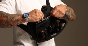 Man sliding his phone into the Faraday Cage in the SLNT® Concealed Carry Faraday Sling