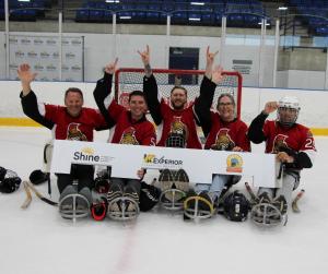 team members on sleighs on the ice ready to play sleigh hockey