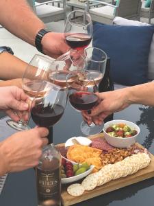 Close up of hands holding wine glasses over a charcuterie platter
