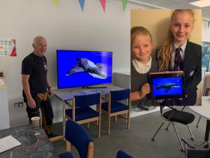 Dr. Steve Etches in the museum's discovery, along with several children holding a tablet featuring "Ava the pliosaur".