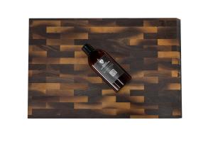 Bottle of STEELPORT Board Conditioner laying on a STEELPORT SteelCore end-grain cutting board