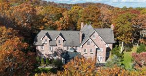 Aerial view of Twickenham House Tudor Wedding Venue with red brick exterior and gabled roofs surrounded by colorful autumn trees