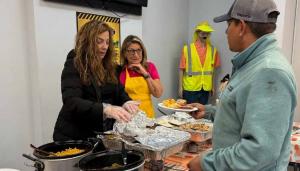 Staff Zone branch team serving Thanksgiving meals to construction workers at a decorated table with cornbread, slow cookers, and autumn-themed décor during annual gratitude event.
