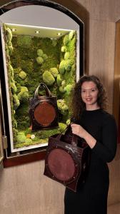 Founder and designer Tanja Störchli presenting the Abdimii Lizard handbag by CICONIIDAE Switzerland in the moss-lined display at the Grand Hotel National Lucerne.