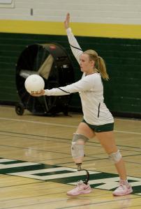Bridget as a teenager on a volleyball court in a team uniform getting ready to serve the ball.