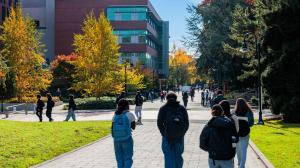 A building in the background with people walking towards it in the foreground.