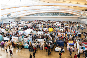 Top-down view of a large vendor hall with shoppers at a Handmade Arcade event.