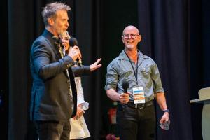 Shane Krider and Myles presenting on stage at a Prosperity Of Life Super Sunday event.