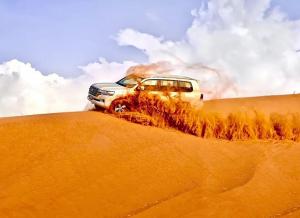 White 4×4 Land Cruiser driving through the red sand dunes of Lahbab Desert during an adventurous Desert Leap Safari tour in Dubai.