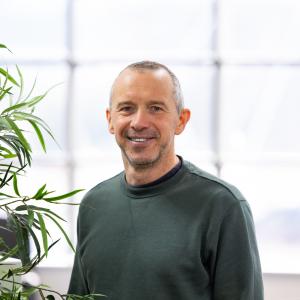 Nairn Robertson smiling and wearing a dark green jumper in a portrait photo