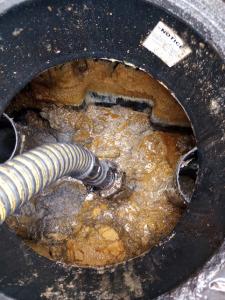 Grease trap cleaning operation showing FOG and sludge being pumped out with a pipe, demonstrating professional grease removal and grease pumping services.