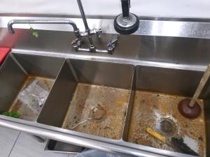 Professional grease trap cleaning in progress on a dirty grease trap, showing grease removal, grease pumping, and FOG management.