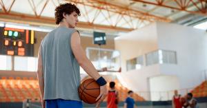 Young basketball player on court with his teammates playing in background.