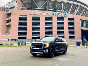 Black GMC Yukon SUV from Starline Town Car & Limousine Service parked in front of Seattle’s Lumen Field, home of the Seahawks and Sounders FC.