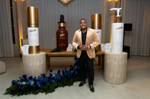 Dr. Carl Truesdale stands beside the Artisa Skincare Masterpiece Collection display, featuring sleek gold-and-white packaging that reflects the brand’s blend of medical precision, artistic design, and inclusive luxury.
