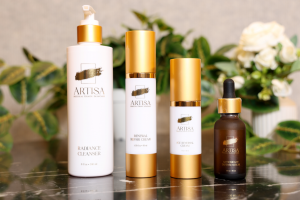 Four Artisa Skincare products from the Masterpiece Collection — cleanser, serum, anti-aging cream, and moisturizer — arranged elegantly on a reflective surface with minimalist gold-and-white packaging symbolizing art, science, and timeless beauty.