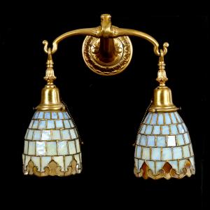 Circa 1910 exceptional double-light gilded bronze wall sconce by Duffner & Kimberly, electrified, with original 6 inch by 5 ½ inch yellow opalescent and amber shades. Estimate: $1,500-$3,000.