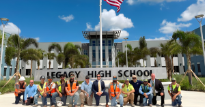 A group of CORE Construction Services of Florida team members and St. Lucie Public Schools representatives stand in front of the new Legacy High School in Tradition, Florida, during its grand opening in August 2025.