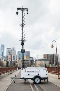 A Mobile Systems Pro Trailer is set up on a bridge. The 33ft mast includes three cameras, floodlights, a loudspeaker, and other security equipment