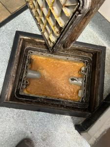 A full grease trap in a San Bernardino restaurant showing accumulated fats, oils, and grease that require professional cleaning.