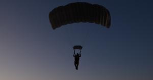 Image of a man descending with his parachute open.