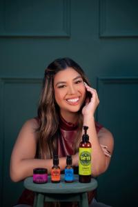 Venezuelan singer-songwriter Gigi Méndez smiles while posing with Setú® Skincare for Men products, including the cleanser, serum, moisturizer, and eye cream, representing her new partnership with the Latino-founded skincare brand celebrating culture and a