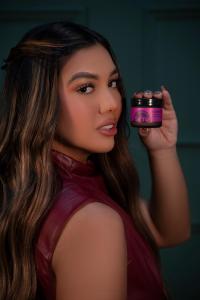 Venezuelan artist Gigi Méndez poses holding the Setú® Moisturizer with Retinol, Açaí, and Maca, highlighting her collaboration with the Latino-founded skincare brand that celebrates culture and authenticity.